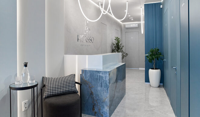 Ресепшн стоматологічної клініки Picasso Dental Clinic в Ужгороді – сучасний інтер'єр у світлих тонах, стильна мармурова стійка, неонове освітлення та комфортна зона очікування