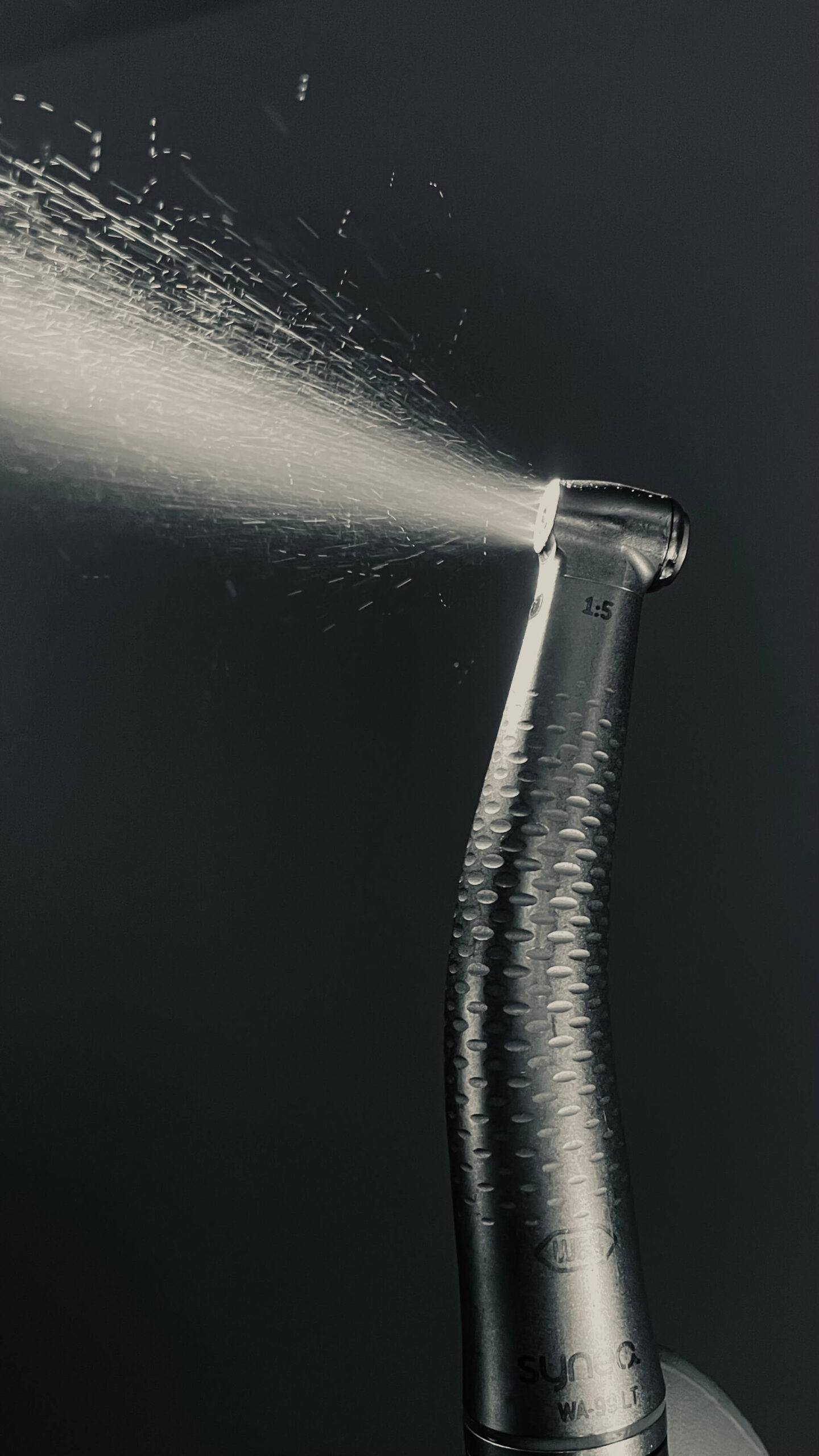 Стоматологічний турбінний наконечник у роботі з розпиленням води під тиском під час професійної гігієни зубів